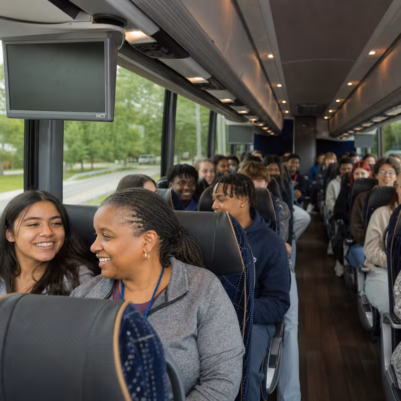 Group boarding a white charter bus for School Transportation transportation in Los Angeles